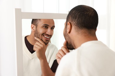 Photo of Smiling man looking at mirror at home