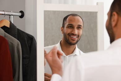 Photo of Smiling man dressing near mirror at home