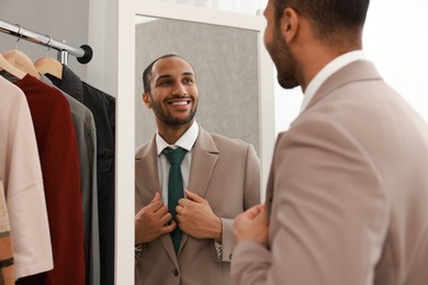 Photo of Smiling man looking at mirror at home