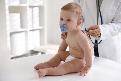 Photo of Pediatrician examining little child with stethoscope in clinic, closeup. Checking baby's health