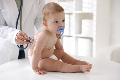 Photo of Pediatrician examining little child with stethoscope in clinic, closeup. Checking baby's health