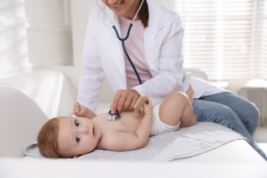 Photo of Pediatrician examining little child with stethoscope in clinic, closeup. Checking baby's health