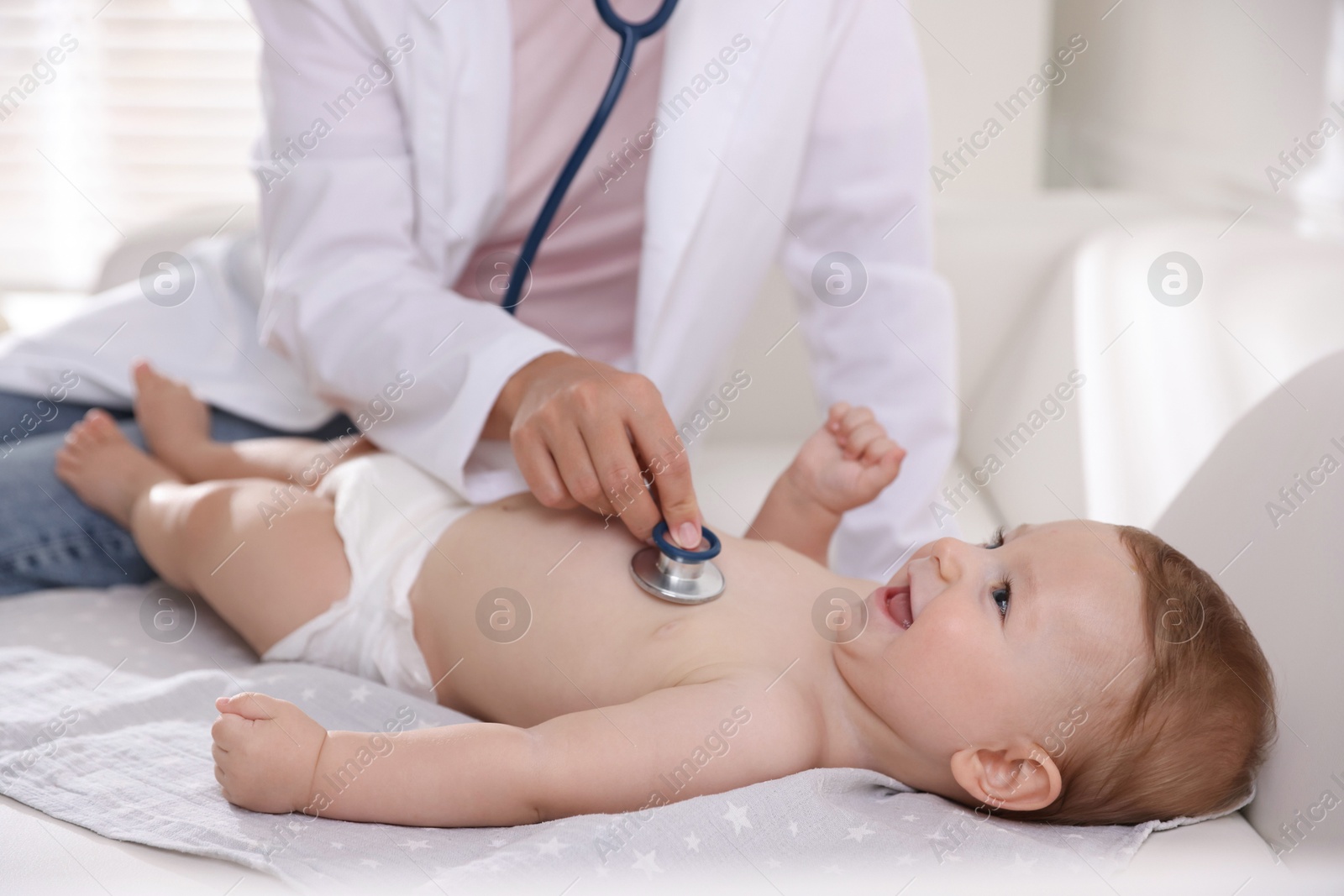 Photo of Pediatrician examining little child with stethoscope in clinic, closeup. Checking baby's health