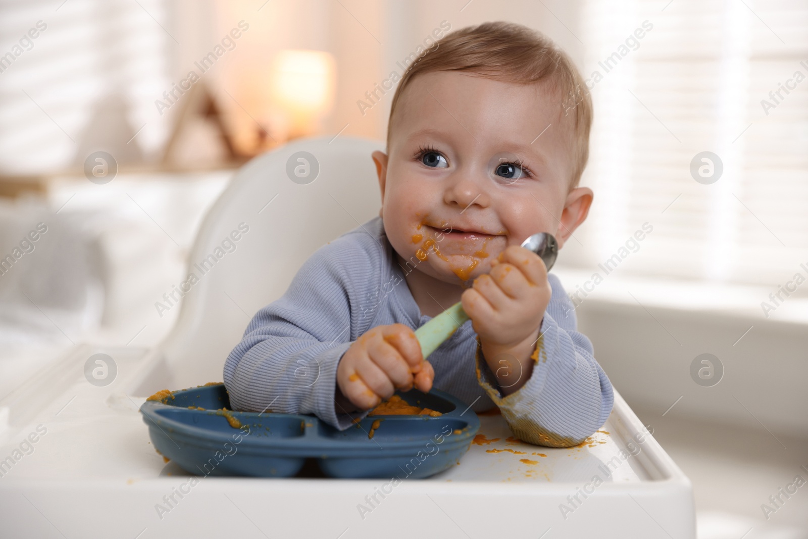 Photo of Cute little baby eating healthy food in high chair indoors