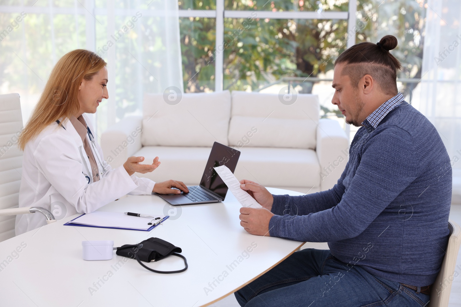 Photo of Nutritionist consulting overweight man at table in clinic