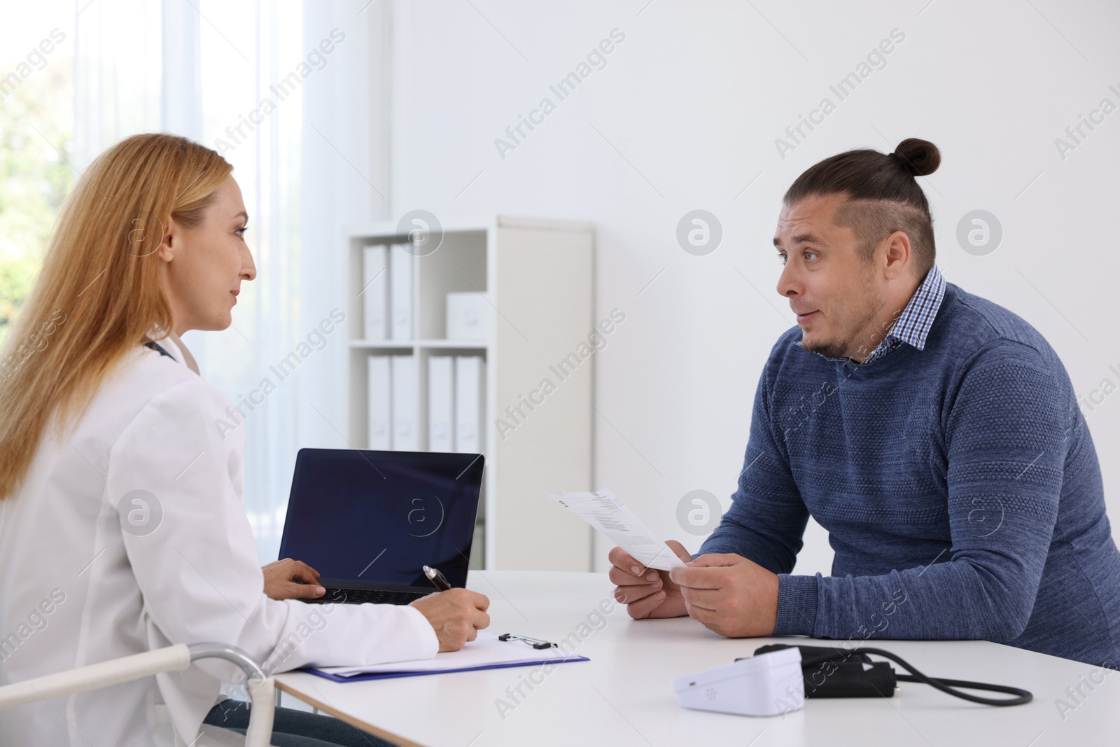 Photo of Nutritionist consulting overweight man at table in clinic