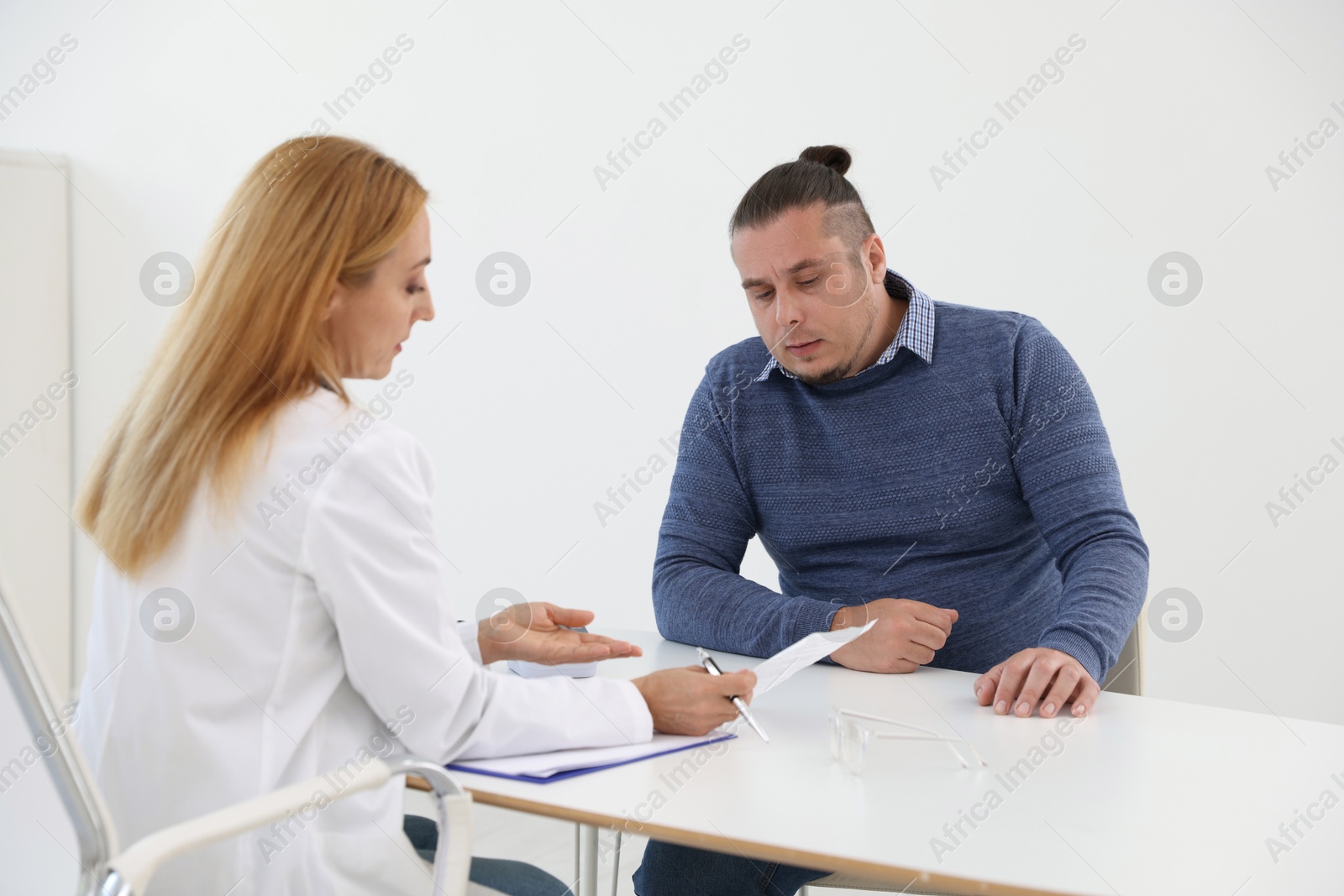 Photo of Nutritionist consulting overweight man at table in clinic