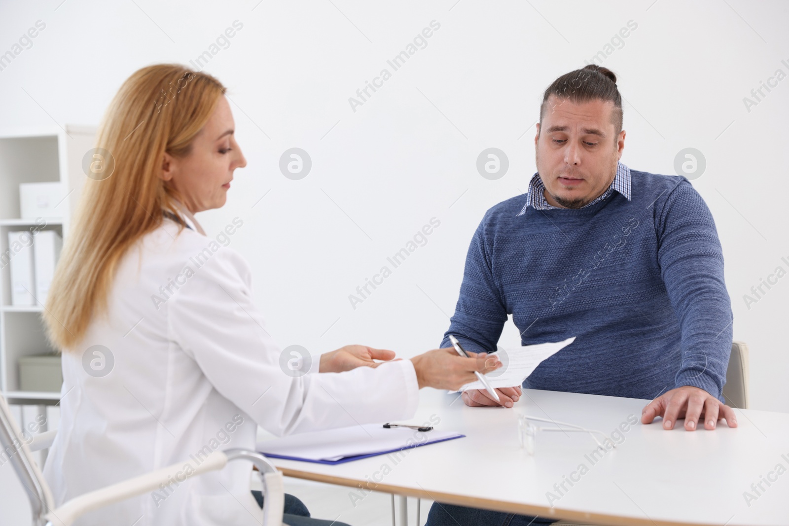 Photo of Nutritionist consulting overweight man at table in clinic