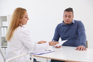 Nutritionist consulting overweight man at table in clinic