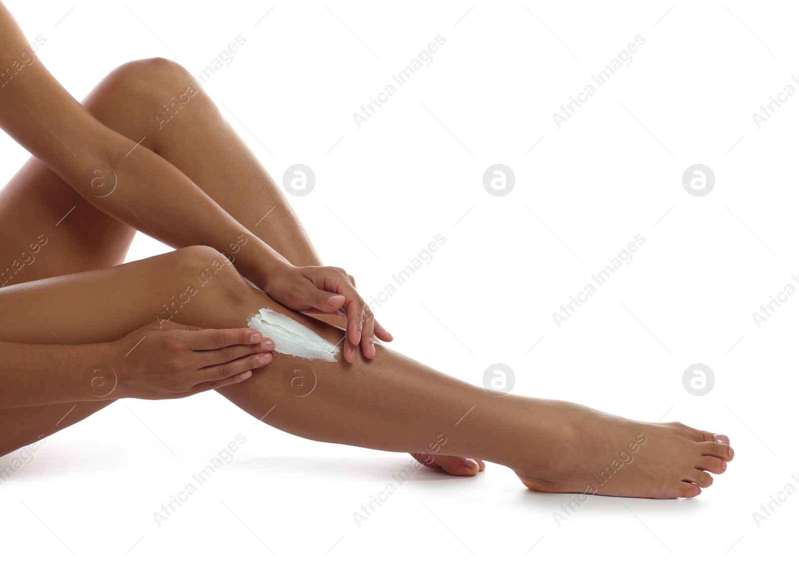 Photo of Woman applying cream onto leg on white background, closeup