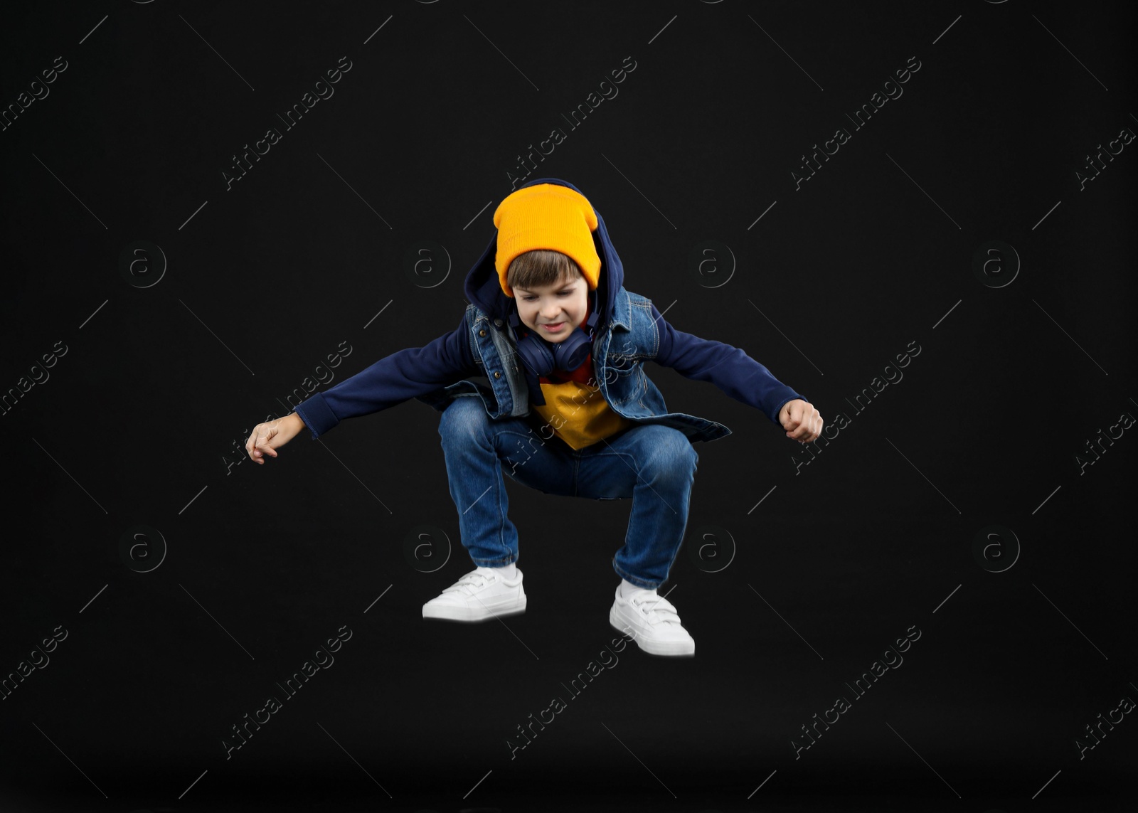 Photo of Happy little boy jumping on black background