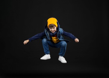 Photo of Happy little boy jumping on black background