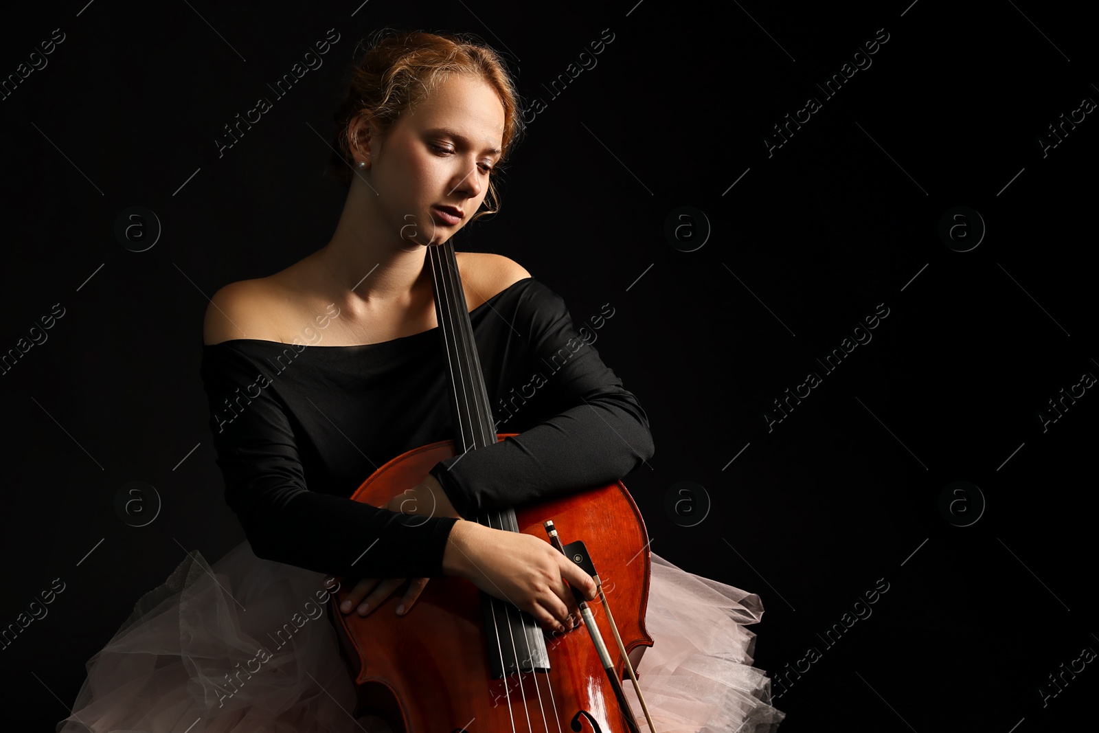 Photo of Beautiful young woman with cello on black background, space for text