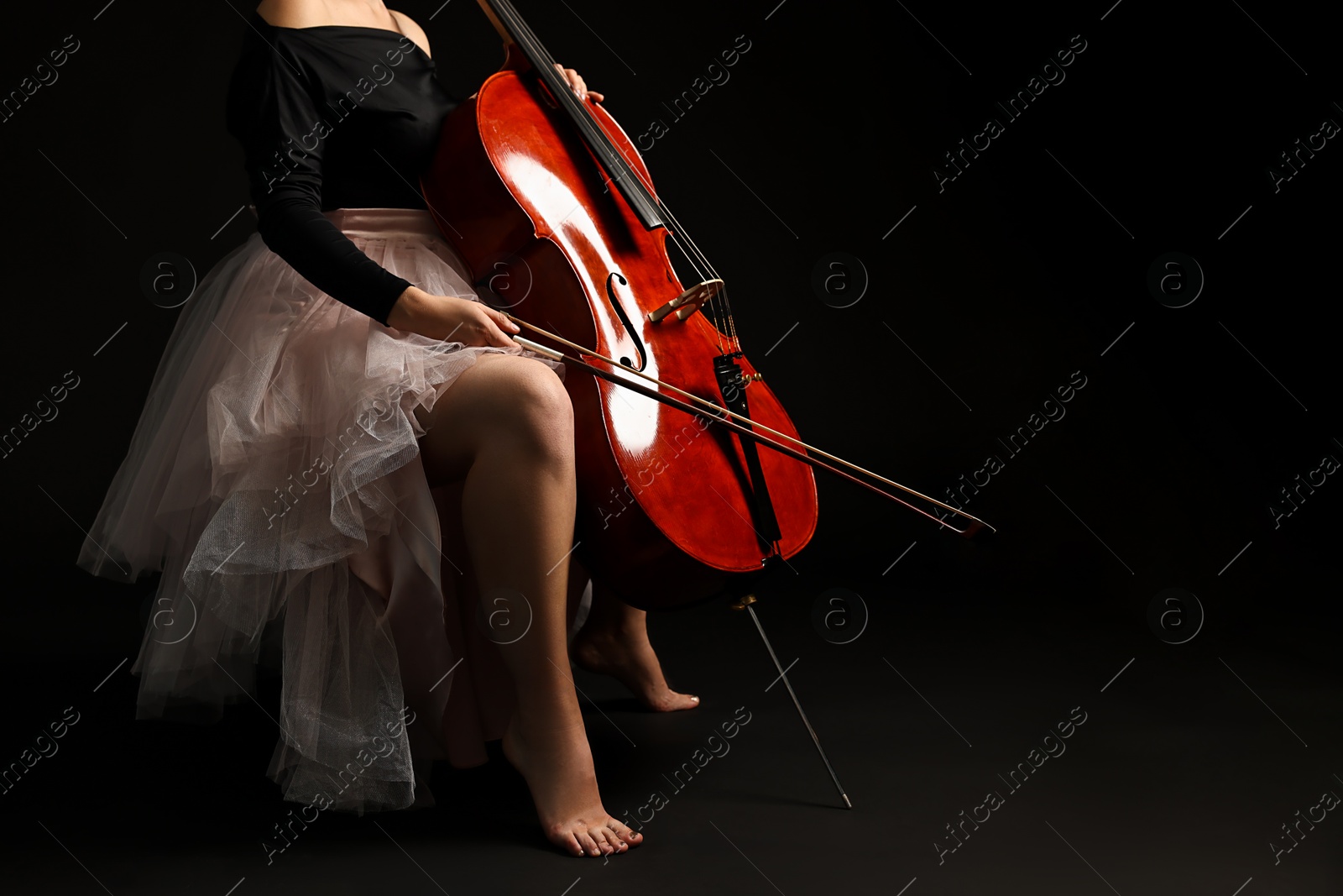 Photo of Young woman with cello on black background, closeup. Space for text