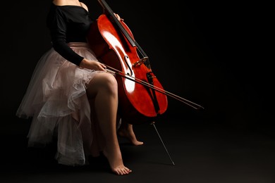 Photo of Young woman with cello on black background, closeup. Space for text