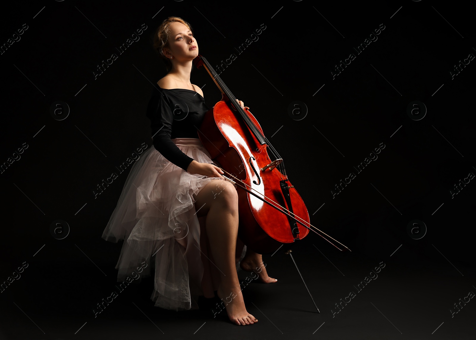 Photo of Beautiful young woman with cello on black background, space for text