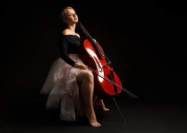 Photo of Beautiful young woman with cello on black background, space for text