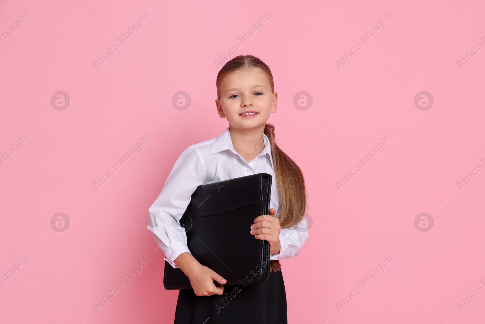 Photo of Little girl with briefcase pretending to be businesswoman on pink background. Dreaming of future profession