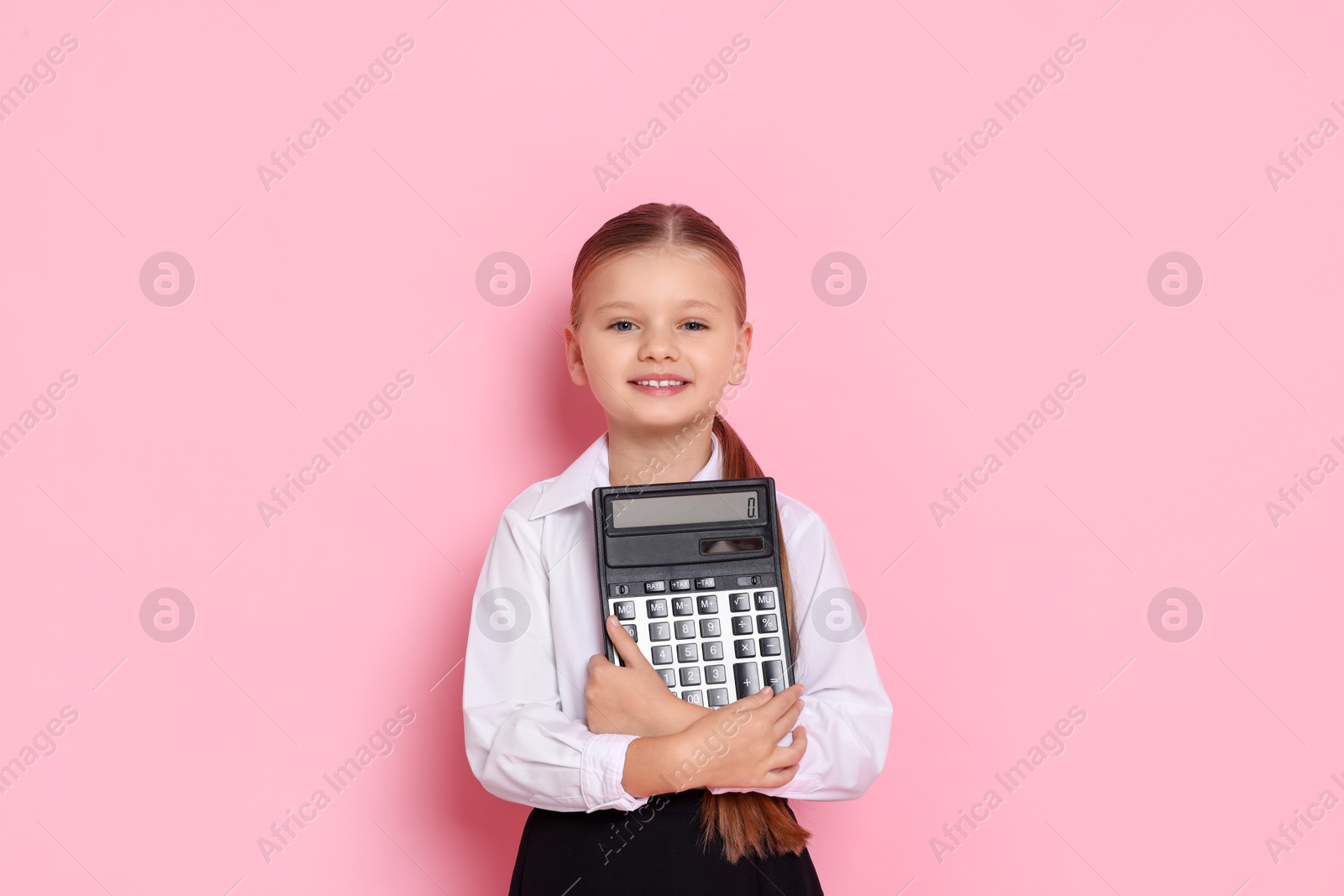 Photo of Little girl with calculator pretending to be accountant on pink background. Dreaming of future profession