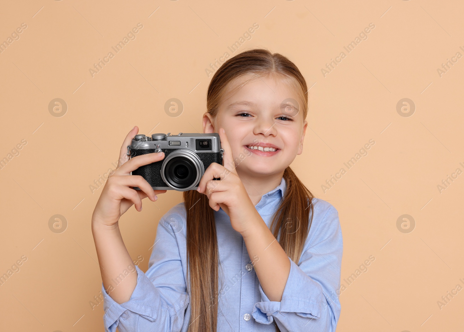 Photo of Little girl with camera pretending to be photographer on beige background. Dreaming of future profession