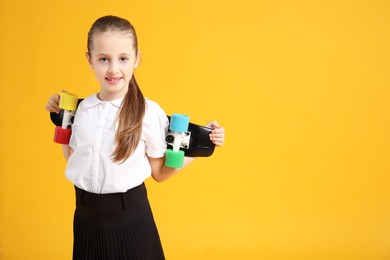 Photo of Little girl with penny board on yellow background, space for text