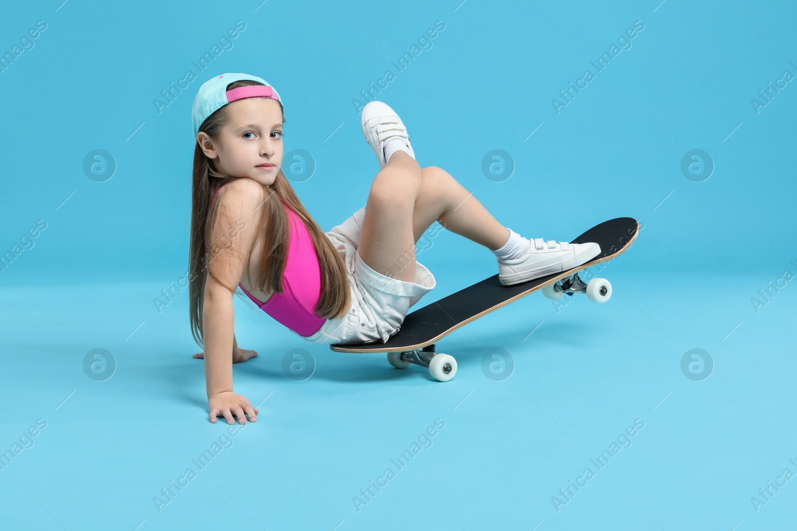 Photo of Stylish girl with skateboard on light blue background, space for text