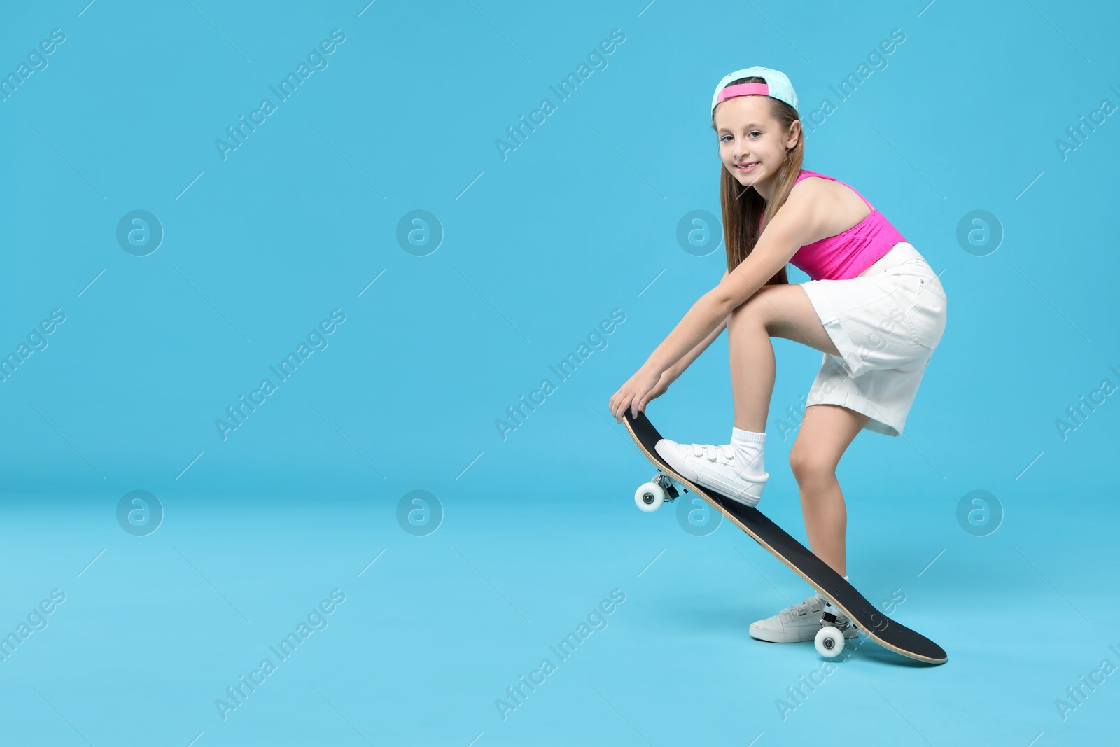 Photo of Stylish girl with skateboard on light blue background, space for text