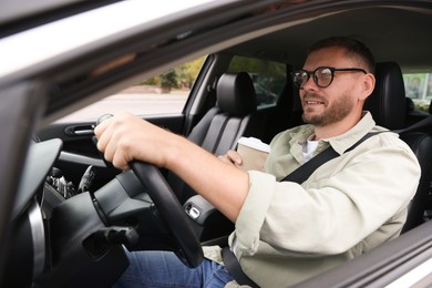 Photo of Man with cup of coffee driving modern car