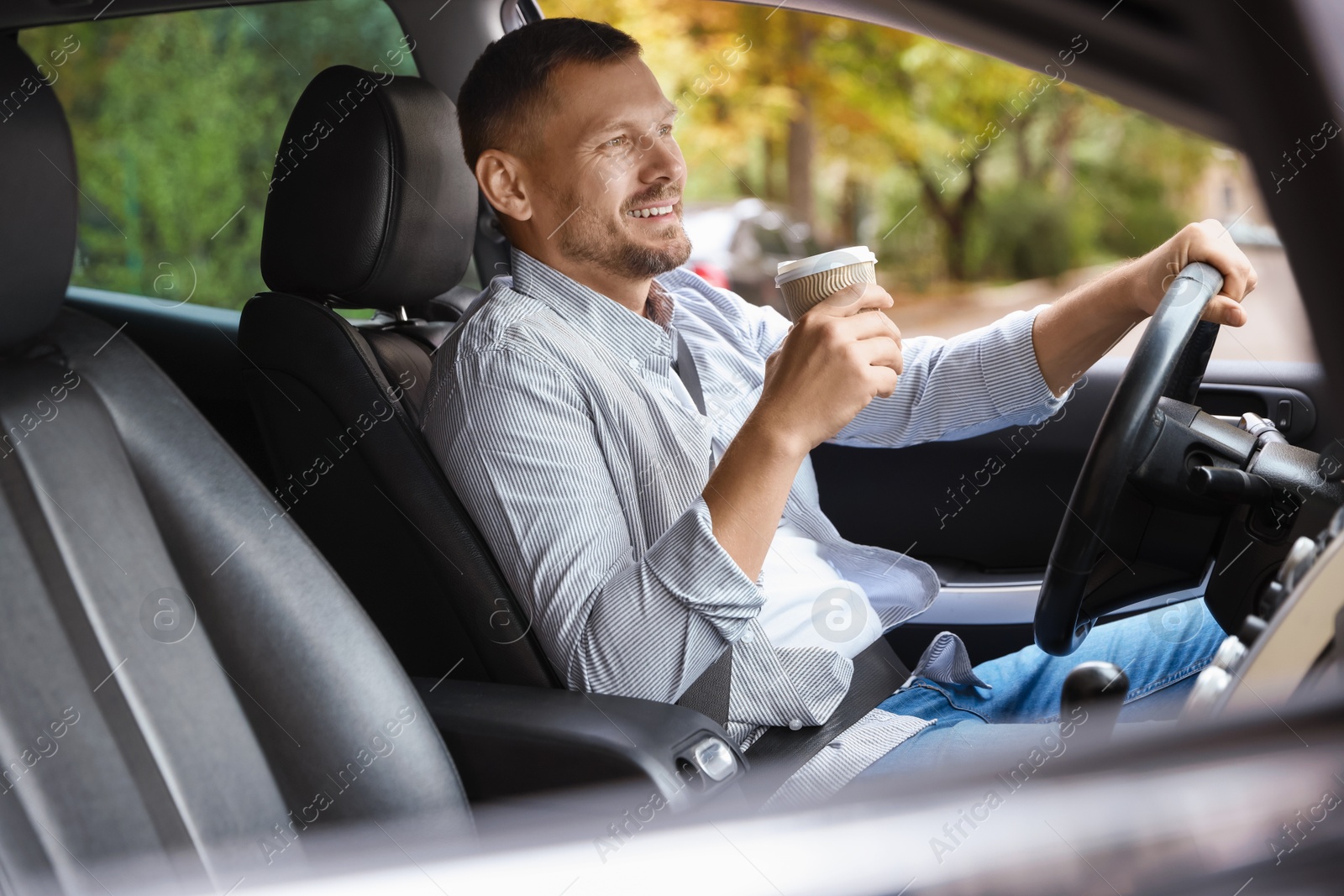 Photo of Man with cup of coffee driving modern car