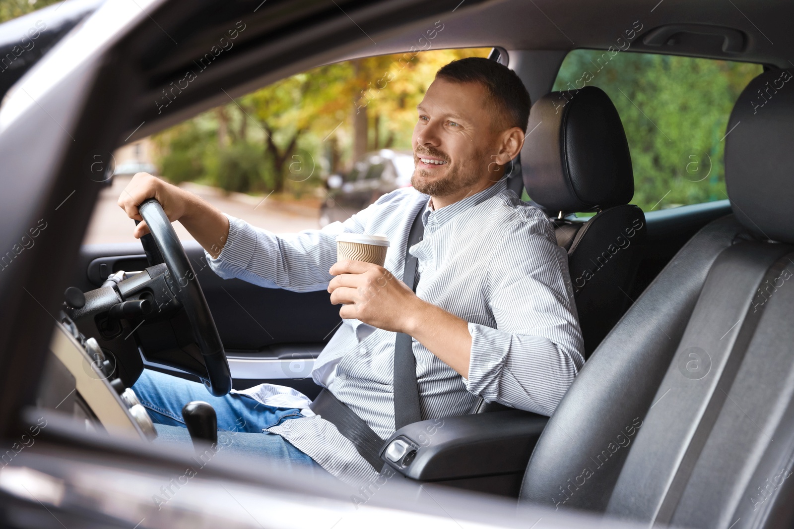 Photo of Man with cup of coffee driving modern car