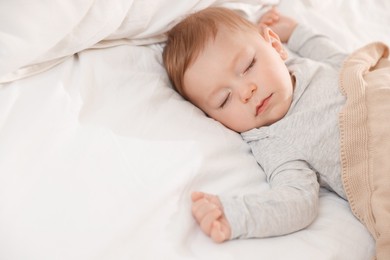 Photo of Cute little baby sleeping on bed at home, space for text