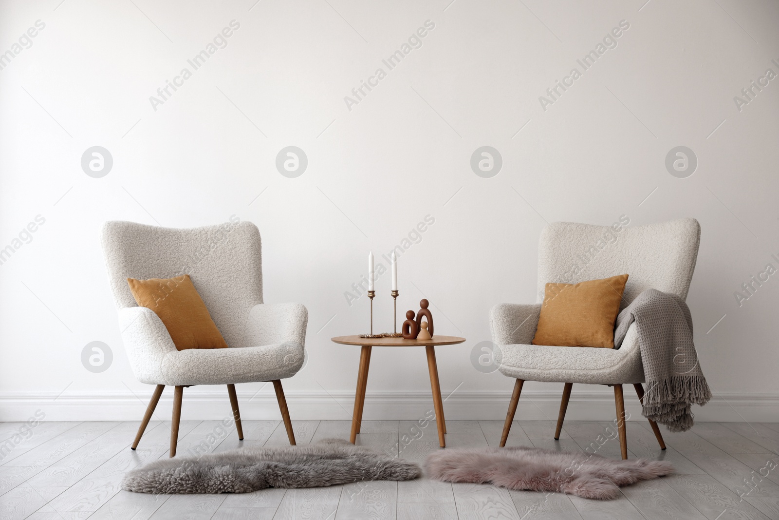 Photo of Soft armchairs and coffee table near white wall indoors