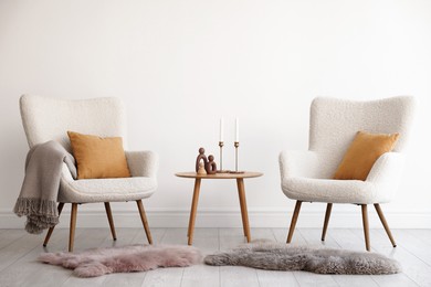 Photo of Soft armchairs and coffee table near white wall indoors