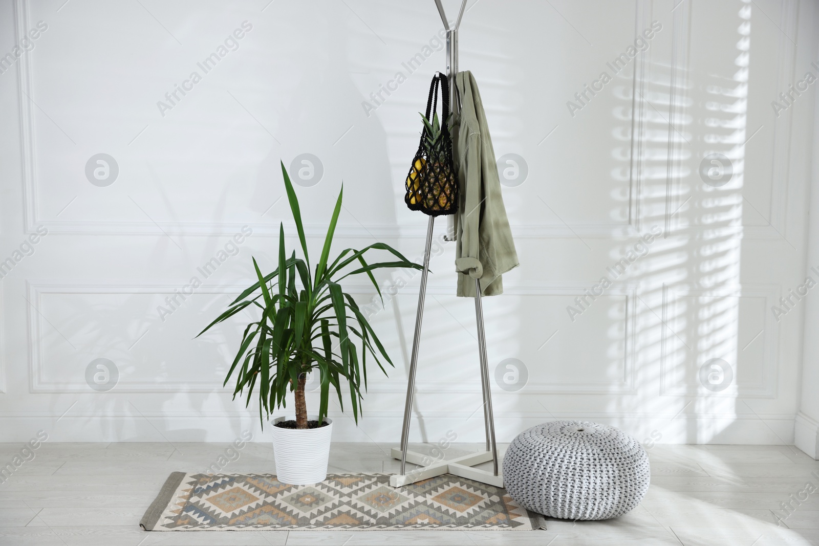 Photo of Macrame bag with fruits and jacket on clothing rack indoors