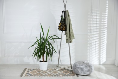 Photo of Macrame bag with fruits and jacket on clothing rack indoors