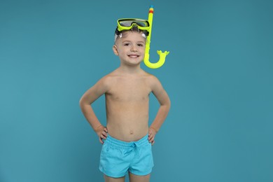 Photo of Cute little boy in beachwear with snorkeling equipment on light blue background