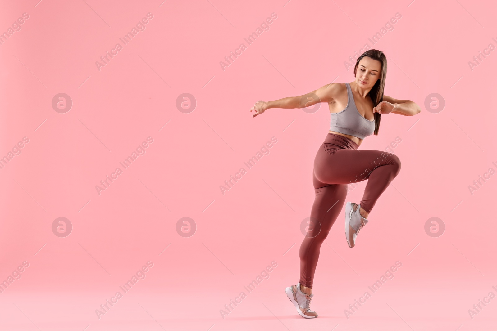 Photo of Woman in gym clothes doing exercise on pink background, space for text