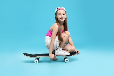 Photo of Stylish girl with skateboard on light blue background