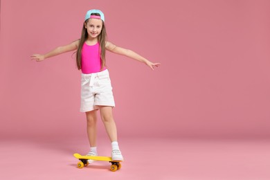 Photo of Little girl with penny board on pink background