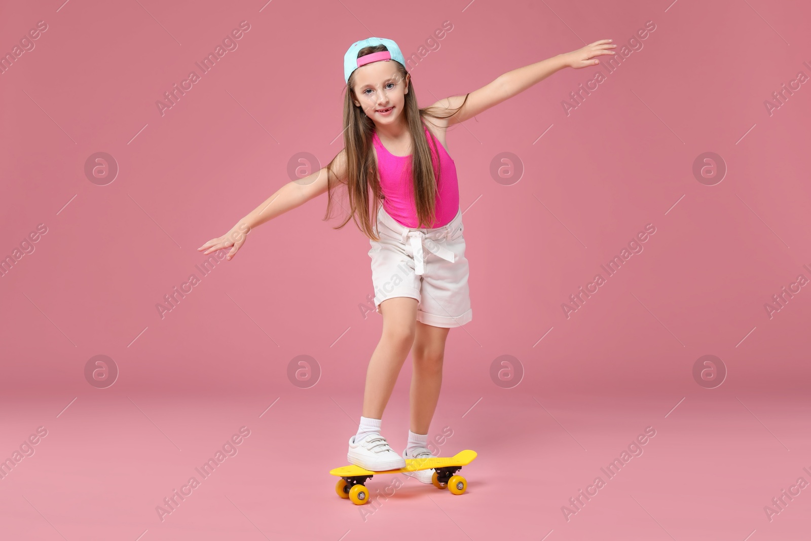 Photo of Little girl with penny board on pink background