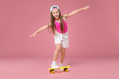 Photo of Little girl with penny board on pink background