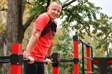 Photo of Man exercising with outdoor equipment in park