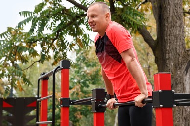 Photo of Man exercising with outdoor equipment in park