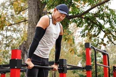 Photo of Man exercising with outdoor equipment in park