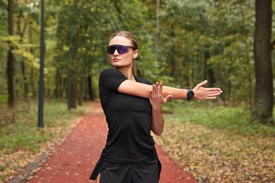 Photo of Young athletic woman stretching in park. Healthy lifestyle