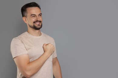 Photo of Man making promise on grey background, space for text. Oath gesture