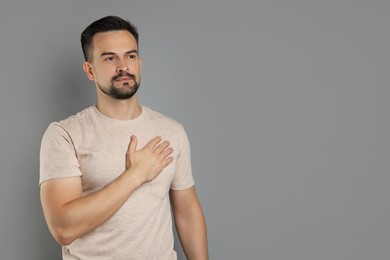 Photo of Man making promise on grey background, space for text. Oath gesture