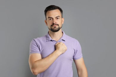 Photo of Man making promise on grey background. Oath gesture