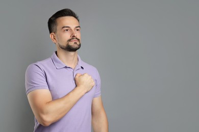 Photo of Man making promise on grey background, space for text. Oath gesture