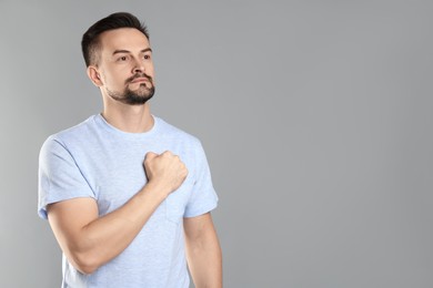 Photo of Man making promise on grey background, space for text. Oath gesture